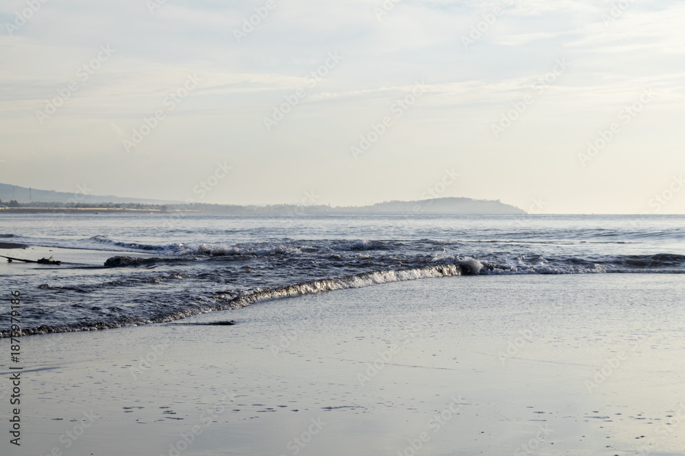 Obraz premium Gentle ocean waves lapping on the shore with natural light creating a serene and peaceful scene perfect for coastal travel or relaxation themes