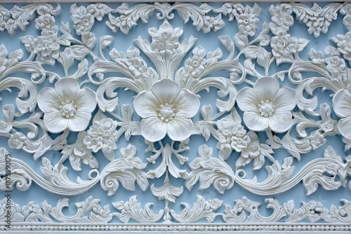 Ornate white floral relief sculpture adorns a pale blue architectural surface