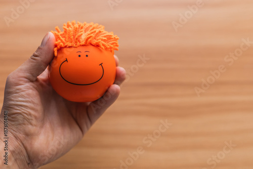 PELOTA DESESTRESANTE DE COLOR NARANJA CON UNA CARA FELIZ SOBRE UNA MESA