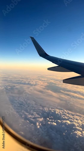 Golden hour light illuminates clouds and airplane wing from a window perspective