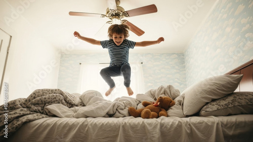 Excited boy in pajamas energetically jumping on a bed with a teddy bear in a cozy bedroom, soft morning light, playful and joyful atmosphere