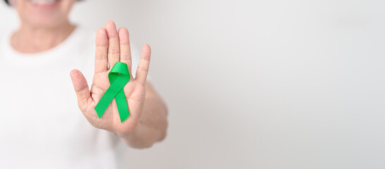Elderly with Green Ribbon for concept of March world Bipolar disorder day, Cerebral Palsy Awareness month, kidney disease Cancer and Traumatic Brain Injury, TBI. Healthcare and world cancer day