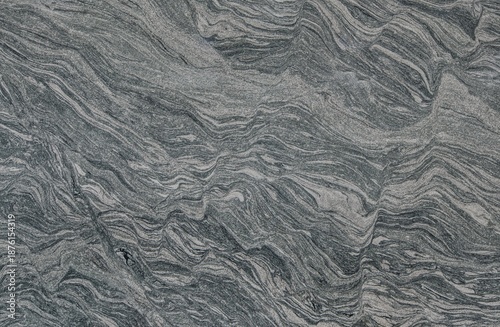 Close-up view of a natural grey and white metamorphic rock surface displaying intricate wavy patterns and geological foliation.