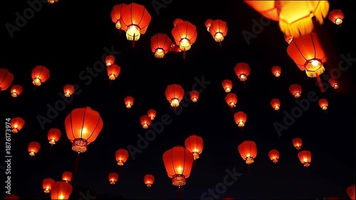 Numerous glowing red lanterns ascend into the dark night sky, creating a beautiful and festive atmosphere.