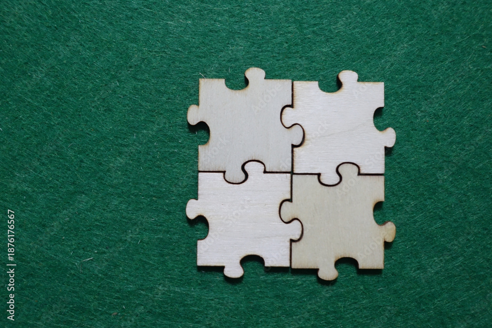 Obraz premium Four wooden puzzle pieces connected on green surface
