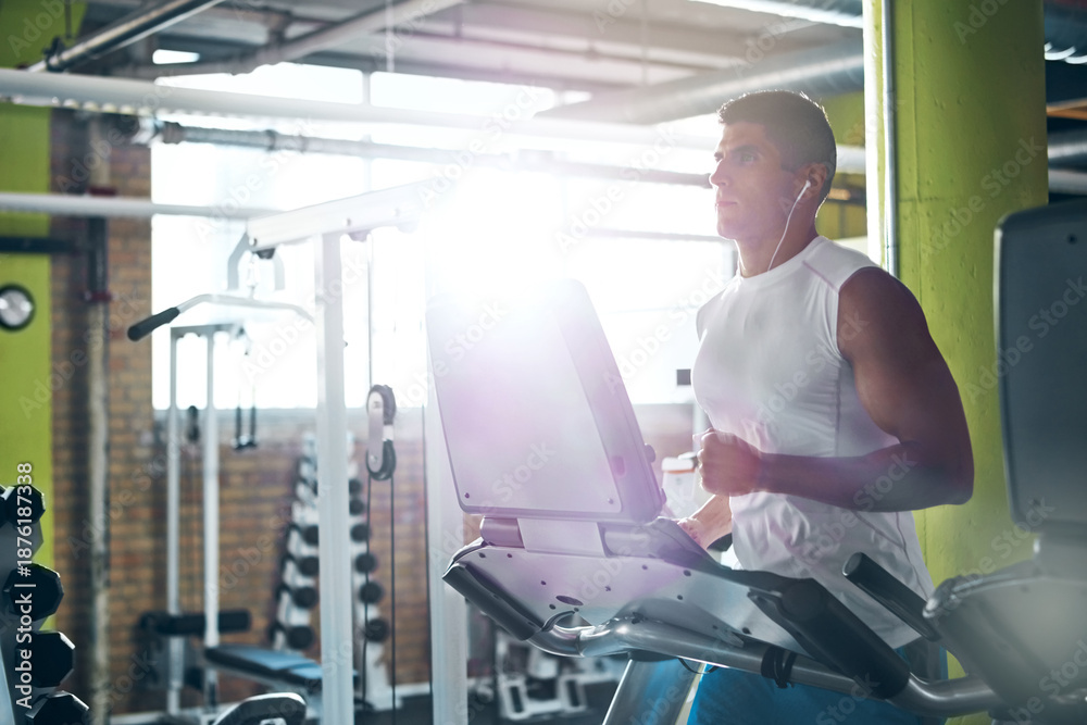 Fototapeta premium Earphones, workout and man running on treadmill for fitness, wellness and listening to audio in gym. Cardio machine, music and person training in health club for exercise, challenge and flare