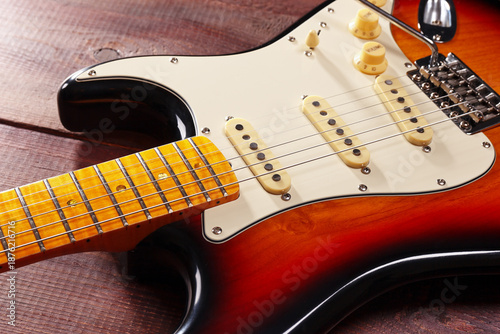 Sunburst guitar closeup on wooden background. Selective focus.