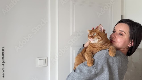 Girl brunette petting cute orange domestic cat at home