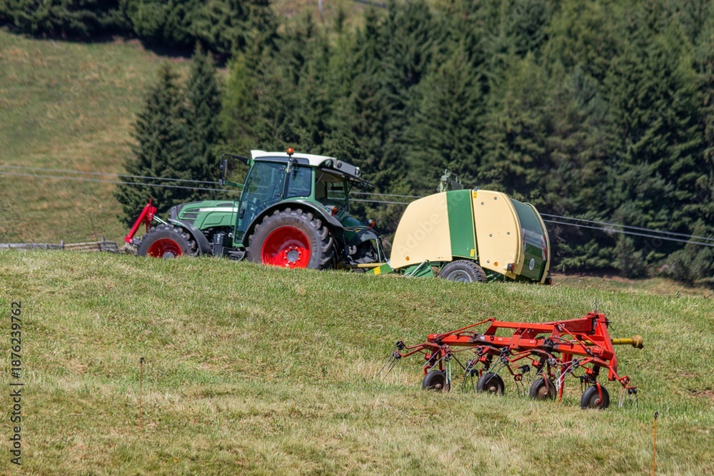 Obraz premium Tractor towing round baler across a grassy field