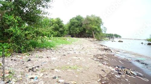 Plastic waste and trash scattered along the shoreline, highlighting marine pollution and environmental issues on the beach.
