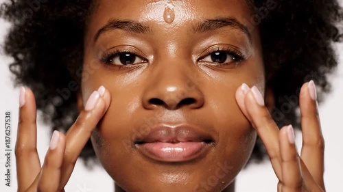 Close-up of person applying clear serum to forehead