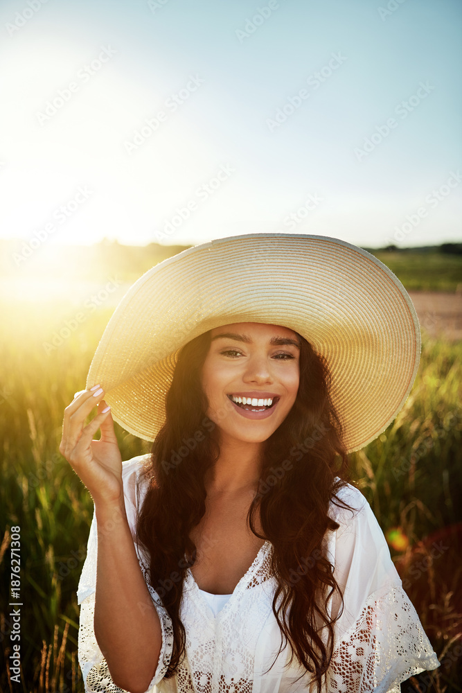 Fototapeta premium Portrait, woman and smile for travel outdoor for summer adventure, explore nature or holiday. Space, female person and straw hat in meadow for peace, calm morning and vacation getaway in countryside
