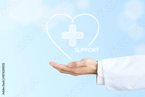 ハートで囲まれた医療マークとサポートの文字を掲げる白衣を着た人物の手