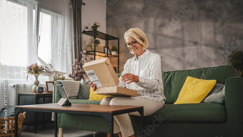 Fotografie Mature sit on sofa woman work from home open delivery package