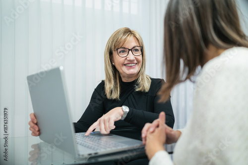 Quadro su tela Esthetician smiling explaining treatment plan on laptop