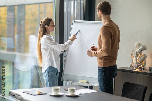 Tableau sur toile Colleagues standing near the flipchart in the office and discussing new project
