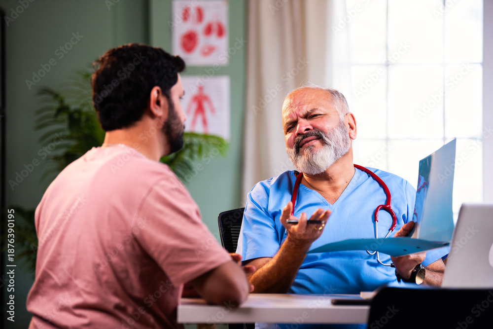 Obraz premium Senior Indian physician writes and explains medicine prescription to young male patient