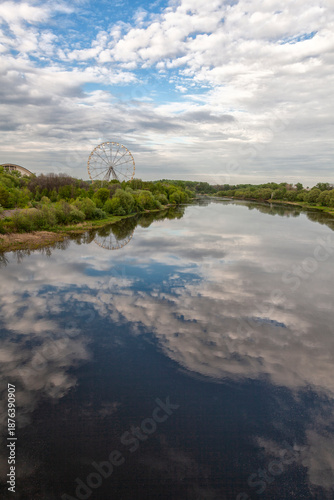 Ferris wheel and river landscape with sky reflection