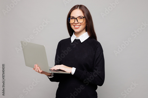 Φωτογραφία Young smiling successful employee IT business woman corporate lawyer she wears black sweater shirt work in office hold use laptop pc computer isolated on plain grey color background studio portrait