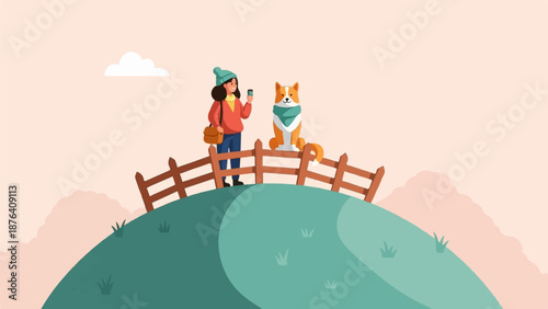 A person and a dog stand on a hill, looking at their phones, with a fence