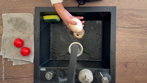 Top view of woman hands washing mushrooms in sink before cooking pizza in home kitchen. Ingredient preparation process, food hygiene routine and everyday home cooking step.