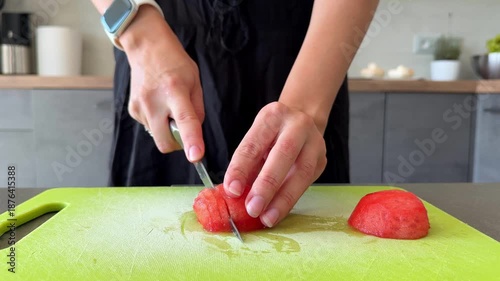 Close up of woman hands finely chopping tomatoes with knife during food preparation in home kitchen. Ingredient processing step, homemade pizza cooking routine and everyday meal preparation at home.