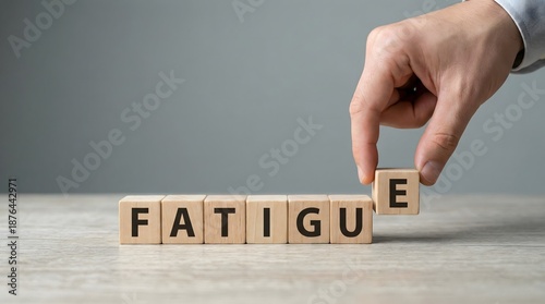 hand placing wooden block with letter E on fatigue word