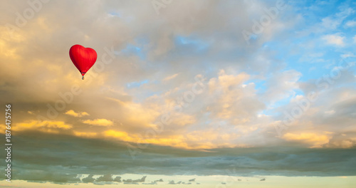 Travel background with a red heart shaped balloon flying in the vast and picturesque sunset sky, romantic travel concept, suitable for St Valentines day