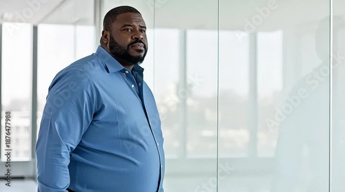 Confident businessman walking through modern office space with large windows