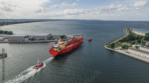 LPG tanker escorted by tugboats on calm sea waters, maritime transport, industrial shipping, logistics, and port operations concept.