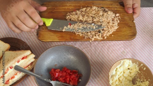 A man prepares tuna and egg sandwiches for lunch.