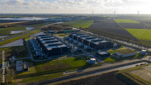 Aerial view of the expansive Data Center Agriport complex with its dark structures contrasting against the patchwork of green and brown fields, Middenmeer, Netherlands.
