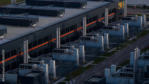 Aerial view of a modern, sprawling industrial complex with dark gray walls and light gray machinery stretching along a paved road, Data Center Agriport, Middenmeer, Netherlands.