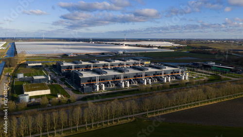 Aerial view of the expansive data center complex with its dark rectangular blocks contrasting with the surrounding bright greenhouses, Middenmeer, Netherlands.