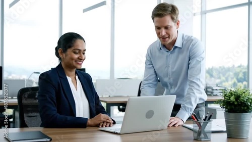 A professional corporate team of smiling businesspeople and executives collaborating around an office table with a laptop and computer during a successful teamwork meeting