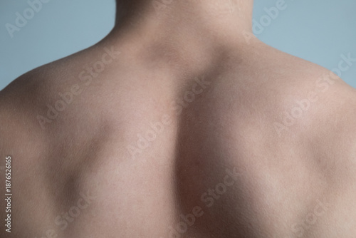 young bodybuilder guy shows wide strong back after exercise and diet. parts of bodies: a man's ass and powerful shoulders.