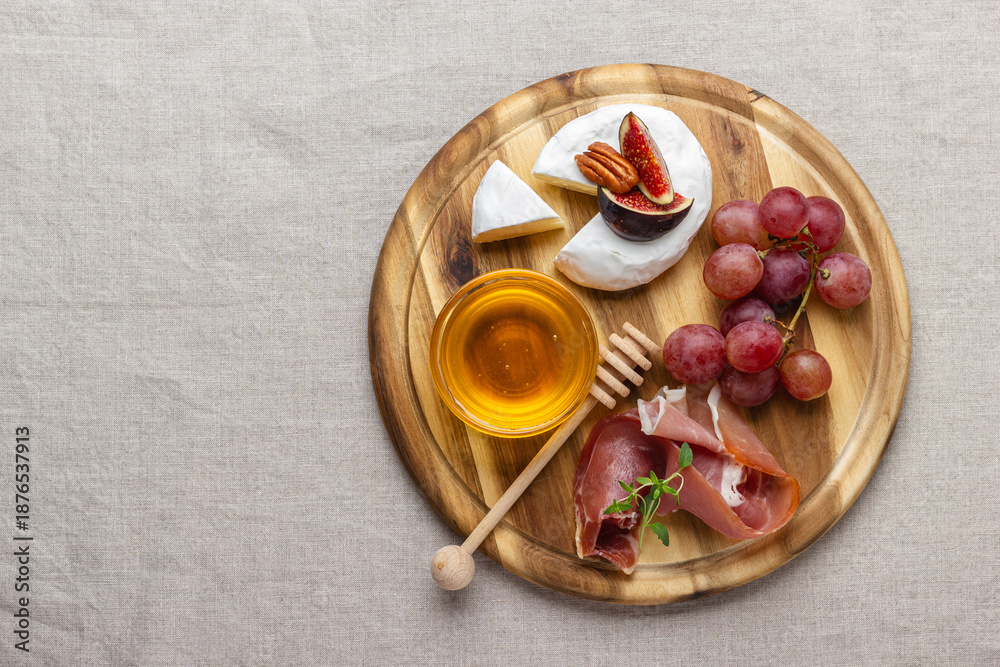 Fototapeta premium Appetizer board with meat, cheese, grapes, nuts, honey and fresh figs.