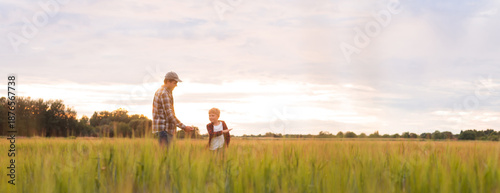 Bild auf Leinwand Farmer and his son in front of a sunset agricultural landscape