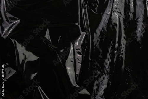 Glossy plastic cellophane texture on black background concept of modern packaging, tactile depth and abstract minimalism in design