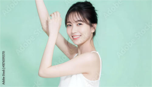 ミントグリーンの背景で両腕を上げる笑顔の女性