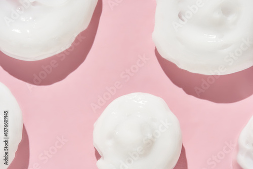 Foto White cream swirls on pink background - smooth texture and skincare conceptual design