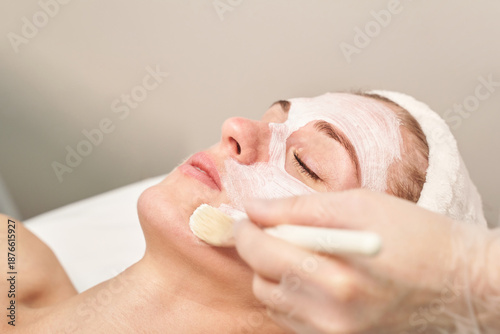 Caucasian female adult receiving facial mask treatment at spa for skincare and relaxation.