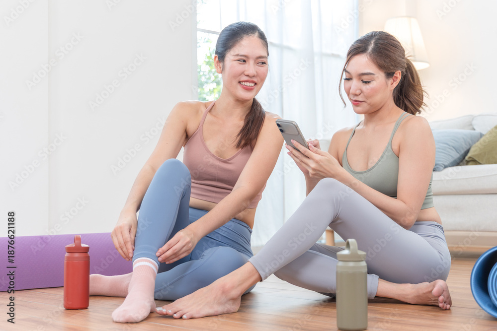Obraz premium Two friends using smartphone after home workout in living room