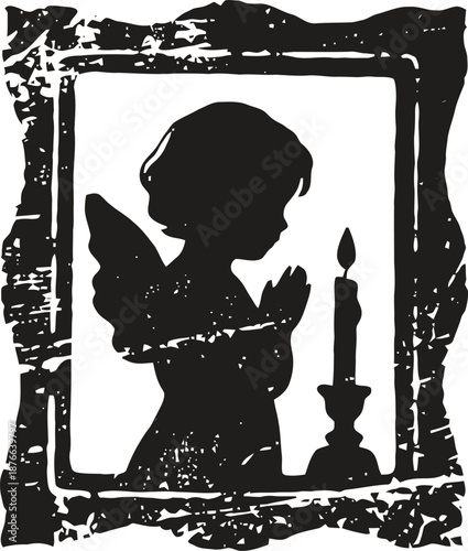 Silhouette of praying angel child with wings near lit candle in rustic frame