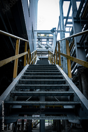 Staircase in a building with a yellow railing. The stairs are very long and the railing is yellow