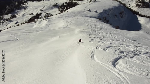 Aerial drone footage of ski touring and freeride skier descending snowy alpine mountain in winter