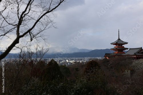 The pagoda of Kiyomizu-dera Temple, the Kyoto cityscape, distant mountains and nearby withered branches.