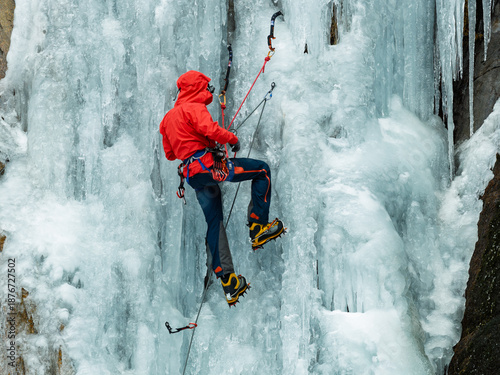 Foto Close up of ice climber using ice tools and crampons on frozen waterfall
