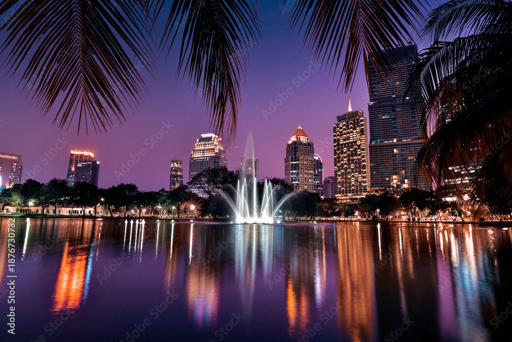 Fototapeta premium Modern city skyline with fountain and reflections at twilight