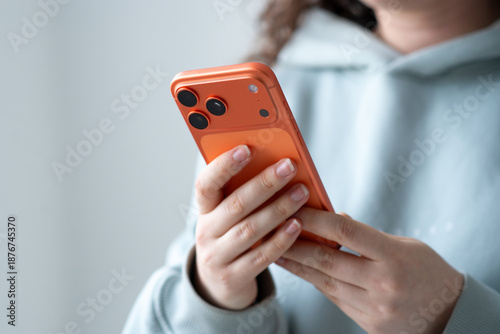 Kyiv, Ukraine. January 14, 2026. Woman using an Cosmic Orange  iPhone 17 Pro smartphone, close-up of modern mobile technology, touch interaction, minimal lifestyle concept.